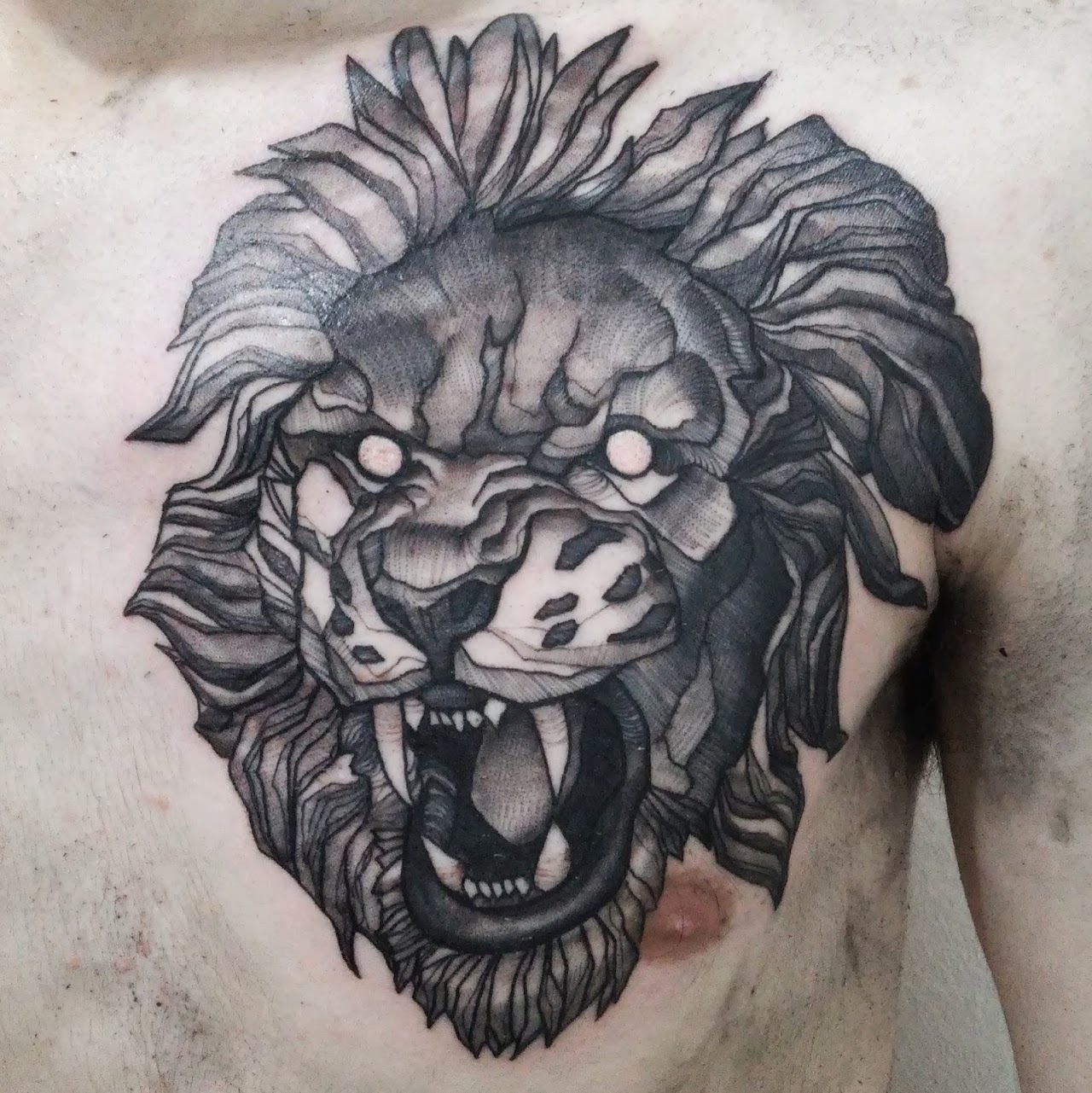 Tatuaje ilustrativo de león en blackwork sobre el pecho