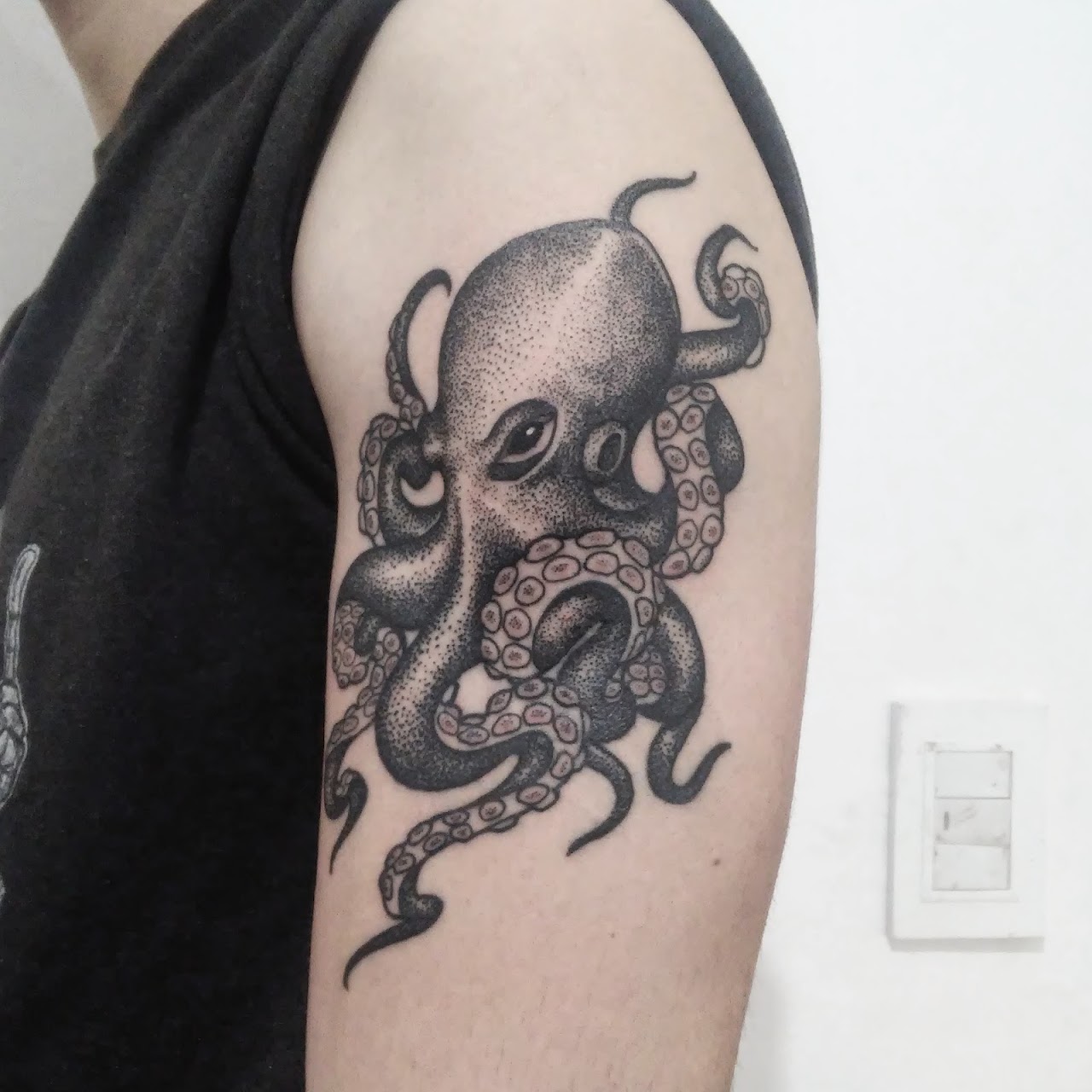 Tatuaje de pulpo en dotwork negro y gris en el brazo